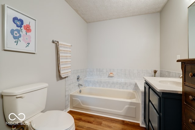 bathroom with a textured ceiling, wood-type flooring, toilet, vanity, and a tub to relax in