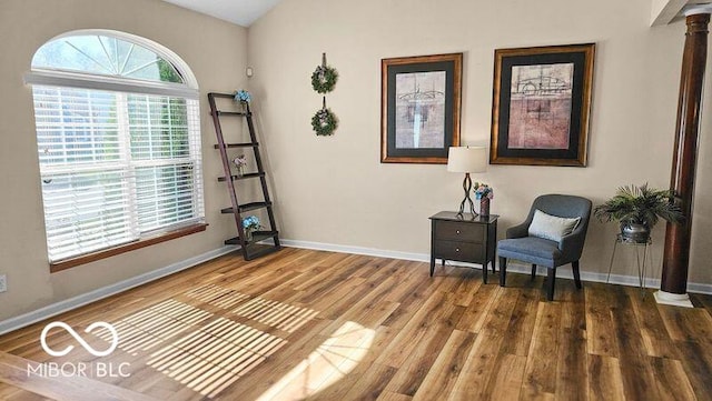 living area featuring lofted ceiling, hardwood / wood-style flooring, and ornate columns