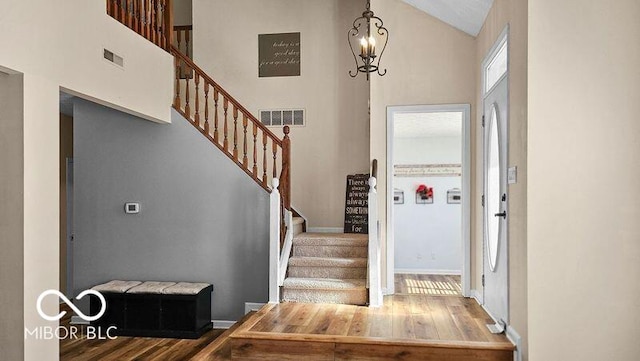 entryway featuring an inviting chandelier, high vaulted ceiling, and wood-type flooring