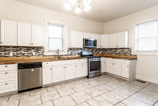 kitchen featuring white cabinets, wood counters, a wealth of natural light, sink, and stainless steel appliances