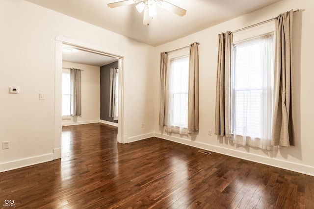 empty room featuring a wealth of natural light, dark hardwood / wood-style floors, and ceiling fan