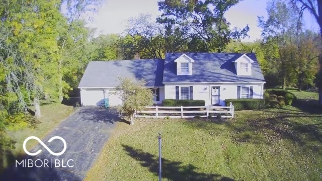 cape cod house with a front yard and a garage