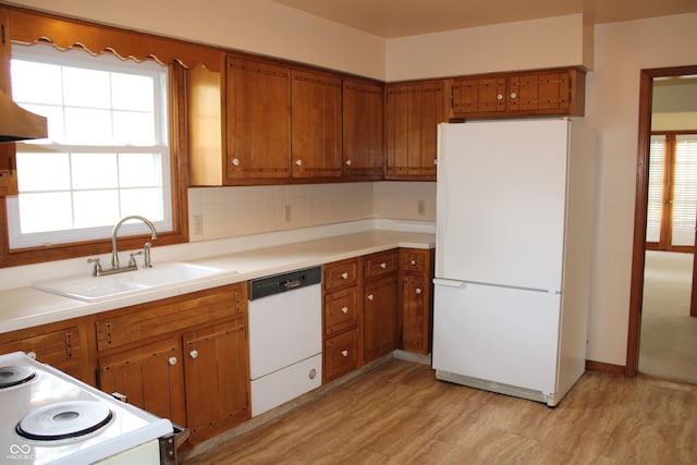 kitchen featuring light hardwood / wood-style flooring, sink, backsplash, and white appliances