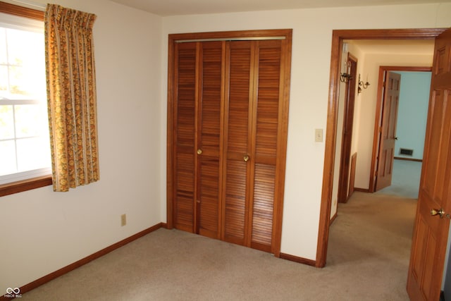 unfurnished bedroom featuring light carpet and a closet