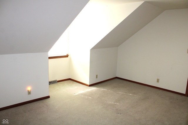 bonus room with lofted ceiling and light colored carpet