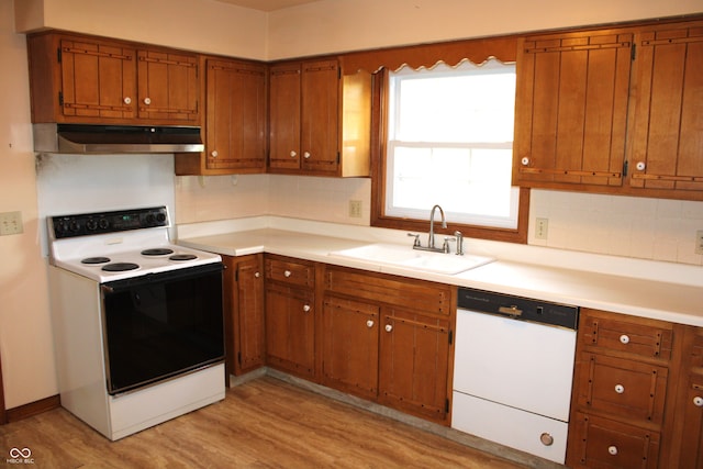 kitchen with white appliances, tasteful backsplash, sink, and light wood-type flooring