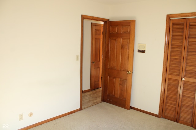 unfurnished bedroom featuring light carpet and a closet