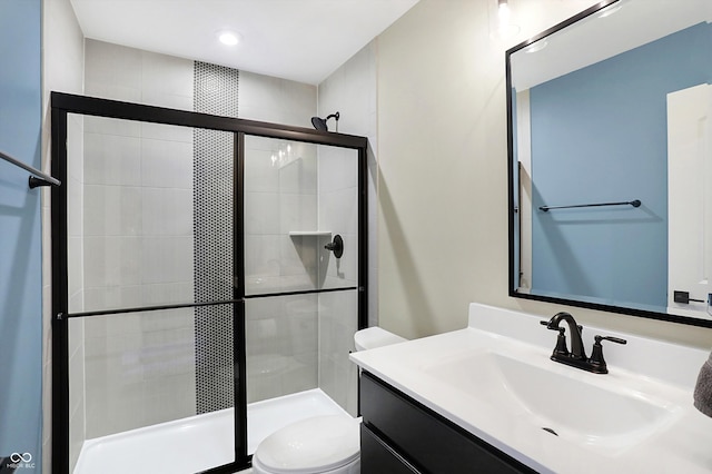 bathroom with vanity, toilet, and a shower with door