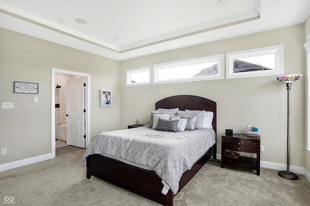 bedroom featuring light colored carpet, a tray ceiling, and connected bathroom