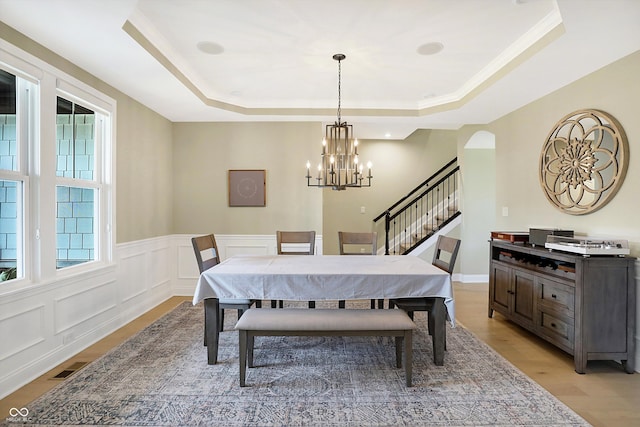 dining room with a chandelier, a tray ceiling, ornamental molding, and light hardwood / wood-style flooring