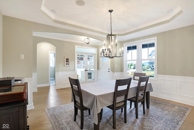 dining room with a raised ceiling, light wood-type flooring, and ornamental molding