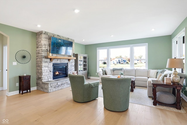 living room featuring light hardwood / wood-style floors and a stone fireplace