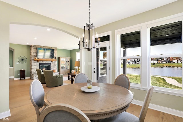 dining space with light wood-type flooring, a fireplace, and an inviting chandelier