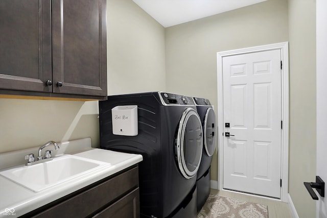 laundry area featuring cabinets, washer and clothes dryer, and sink