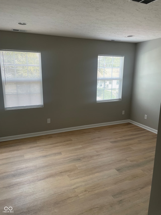 empty room with light hardwood / wood-style flooring and a textured ceiling