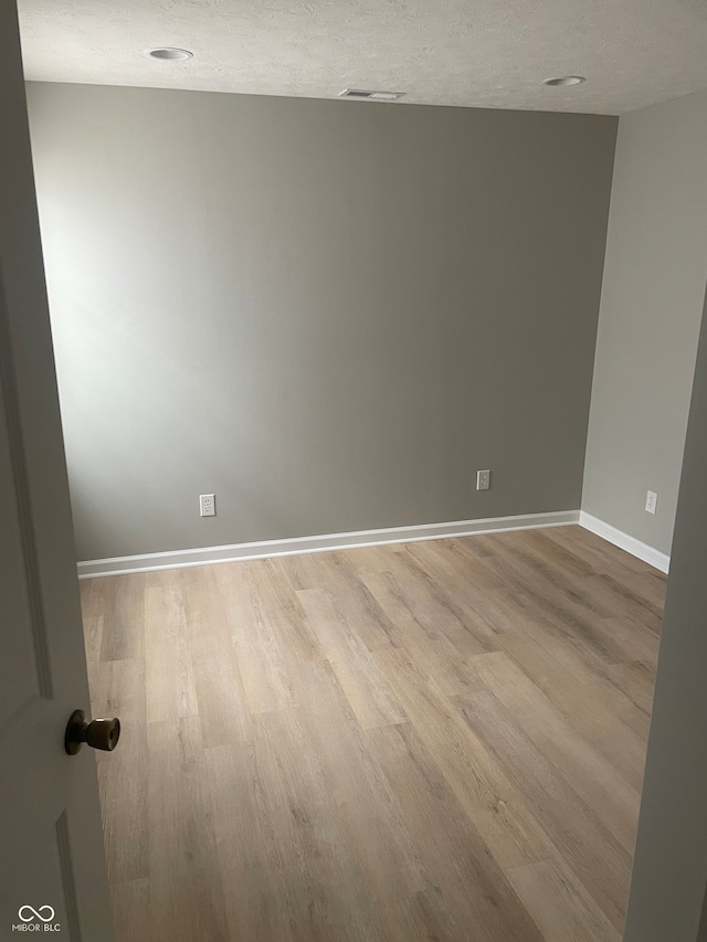 spare room with light hardwood / wood-style floors and a textured ceiling