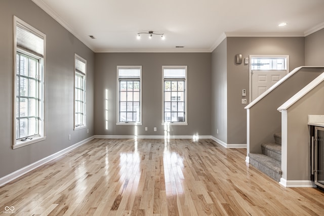 unfurnished living room with crown molding, a healthy amount of sunlight, and light wood-type flooring