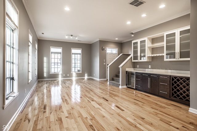 bar with light hardwood / wood-style flooring, ornamental molding, and dark brown cabinets