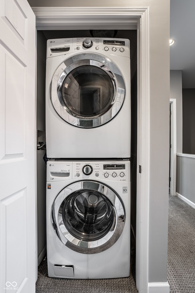 clothes washing area featuring stacked washer and clothes dryer and dark colored carpet