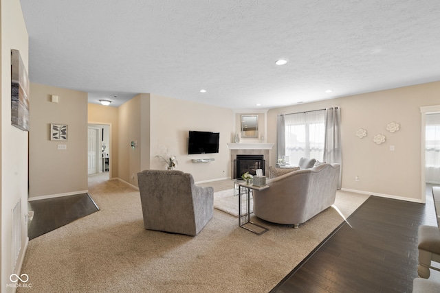 living room with hardwood / wood-style floors, a tiled fireplace, and a textured ceiling