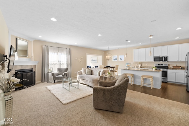 living room with a textured ceiling, hardwood / wood-style flooring, sink, and a fireplace