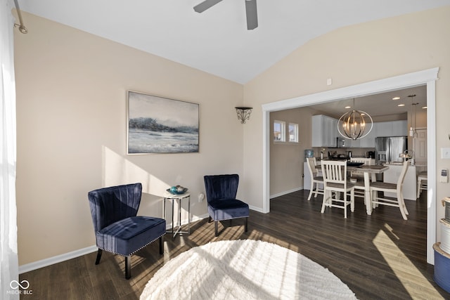 sitting room with dark wood-type flooring, ceiling fan with notable chandelier, and vaulted ceiling