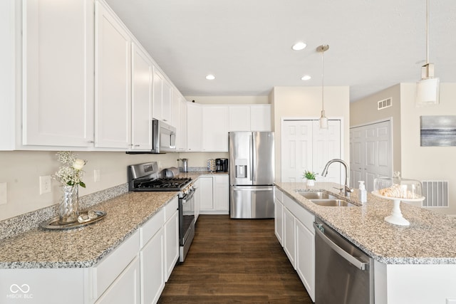 kitchen with appliances with stainless steel finishes, sink, pendant lighting, and white cabinets