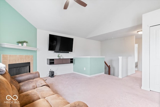 living room featuring lofted ceiling, light carpet, a tiled fireplace, and ceiling fan