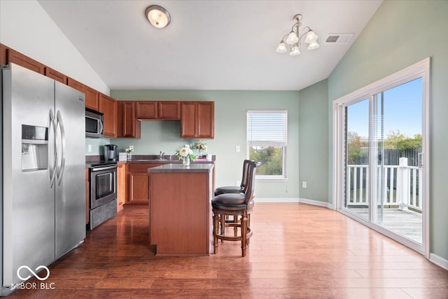 kitchen with a kitchen breakfast bar, a kitchen island, dark wood-type flooring, and stainless steel appliances