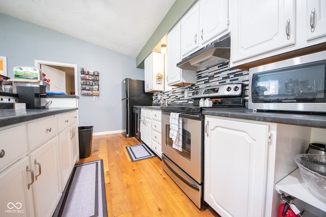 kitchen featuring appliances with stainless steel finishes, lofted ceiling, decorative backsplash, light wood-type flooring, and white cabinetry