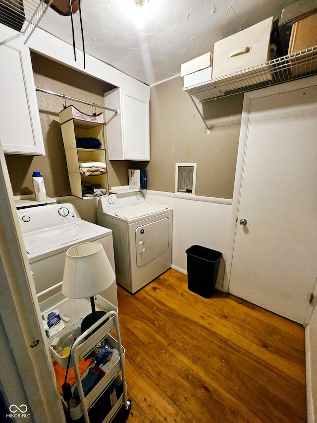 laundry room featuring cabinets, dark hardwood / wood-style flooring, and washing machine and clothes dryer