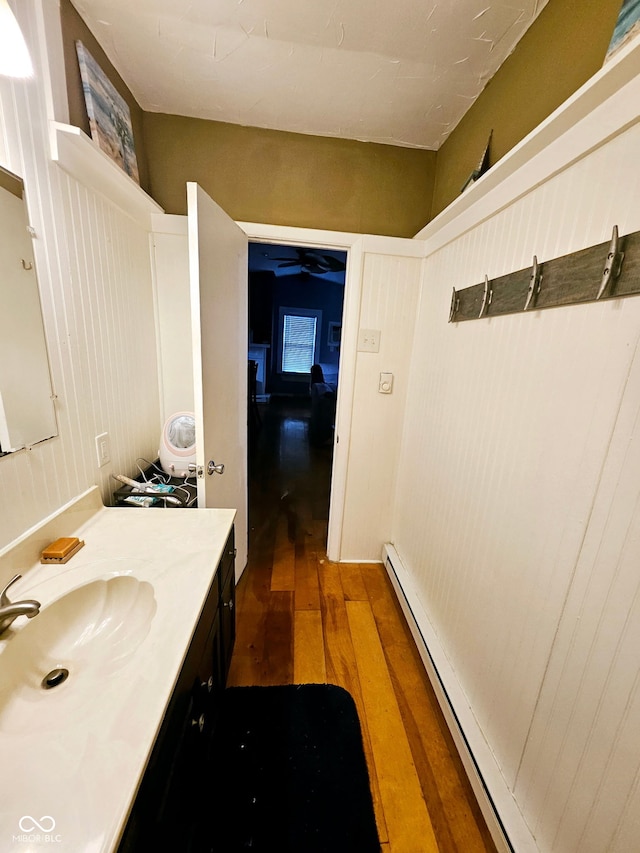 bathroom with hardwood / wood-style flooring, sink, and a baseboard heating unit