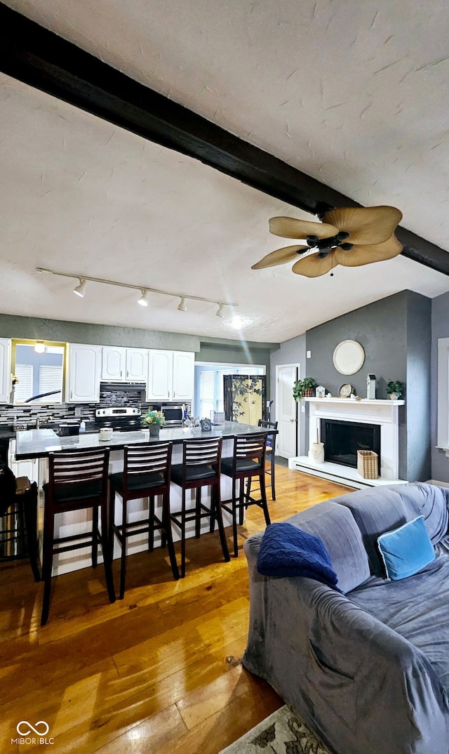 living room with hardwood / wood-style floors, ceiling fan, and vaulted ceiling with beams