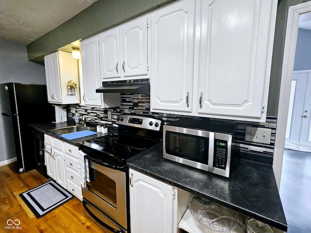 kitchen with sink, appliances with stainless steel finishes, white cabinets, dark hardwood / wood-style floors, and decorative backsplash