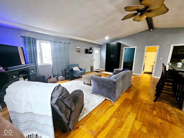 living room with ceiling fan, lofted ceiling with beams, and wood-type flooring