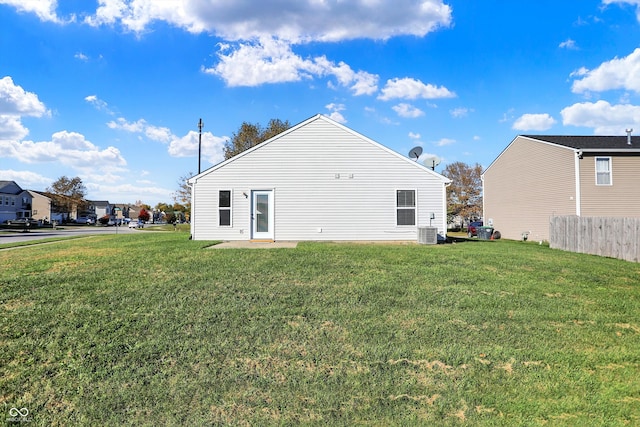 rear view of property featuring cooling unit and a lawn