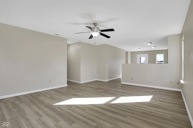 empty room with ceiling fan and light hardwood / wood-style flooring