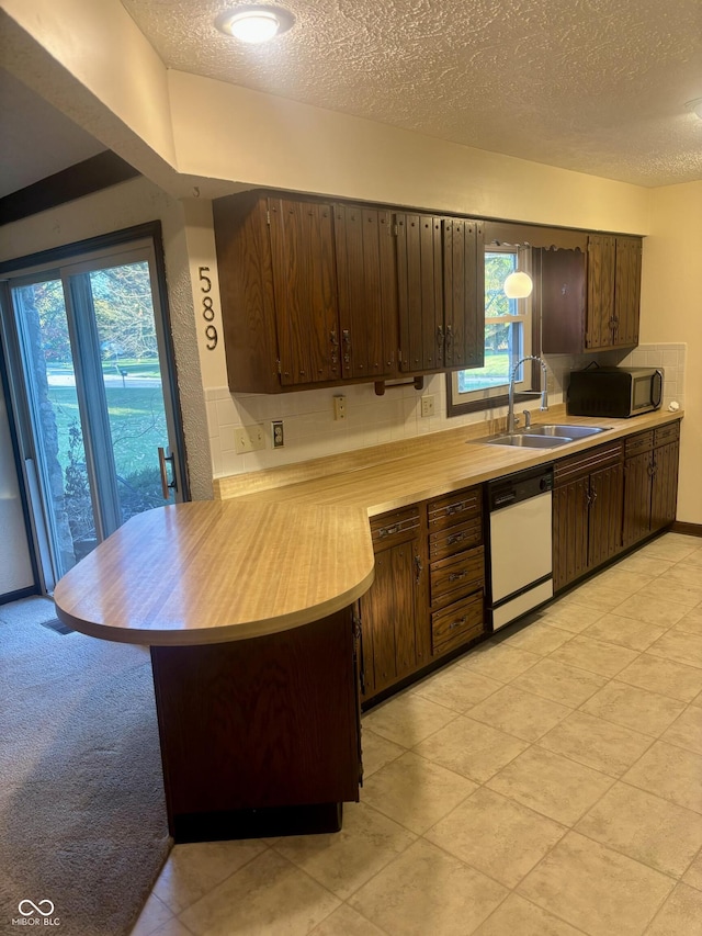 kitchen with dishwasher, a healthy amount of sunlight, sink, and dark brown cabinets