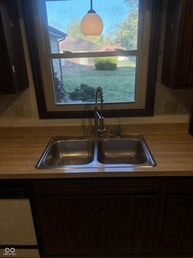 kitchen featuring dark brown cabinetry, backsplash, white dishwasher, and sink