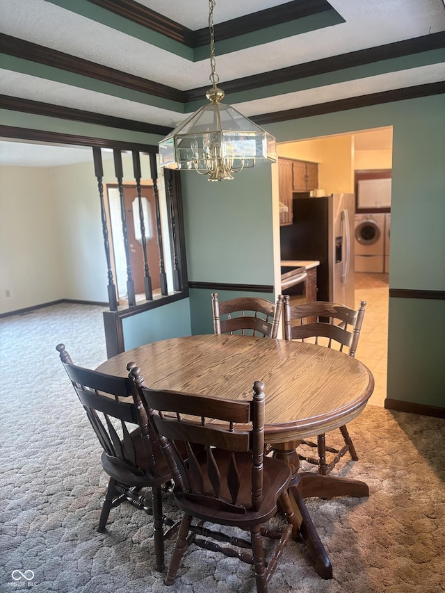 dining area featuring an inviting chandelier, crown molding, washer / clothes dryer, and carpet floors