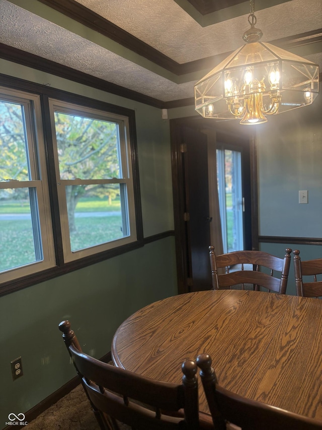 dining area with a notable chandelier, a textured ceiling, a wealth of natural light, and ornamental molding