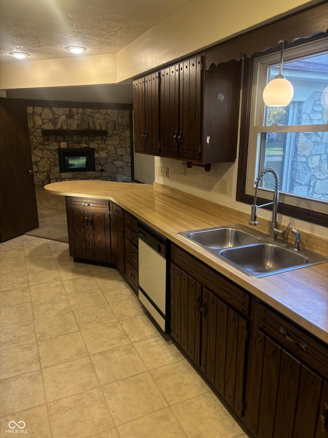 kitchen featuring sink, a fireplace, a textured ceiling, white dishwasher, and decorative light fixtures