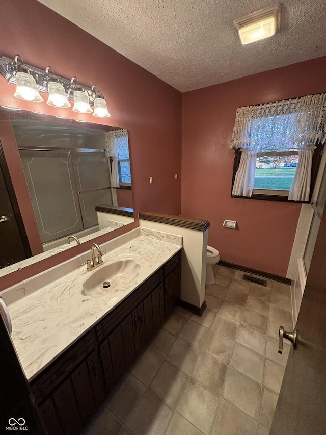 bathroom featuring tile patterned floors, toilet, vanity, a textured ceiling, and walk in shower