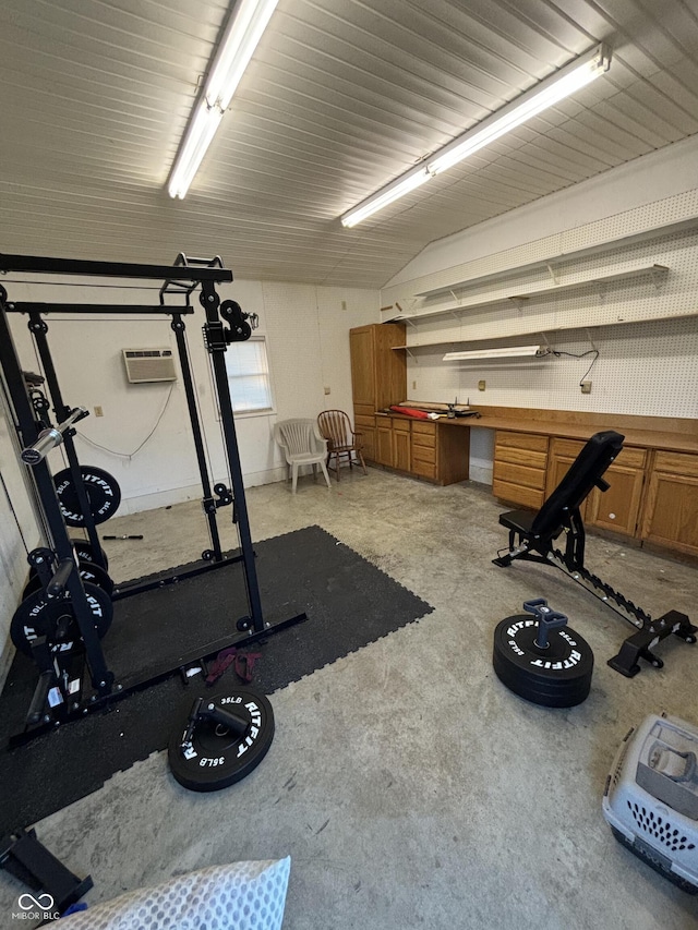 workout room with lofted ceiling, a wall mounted AC, and built in desk