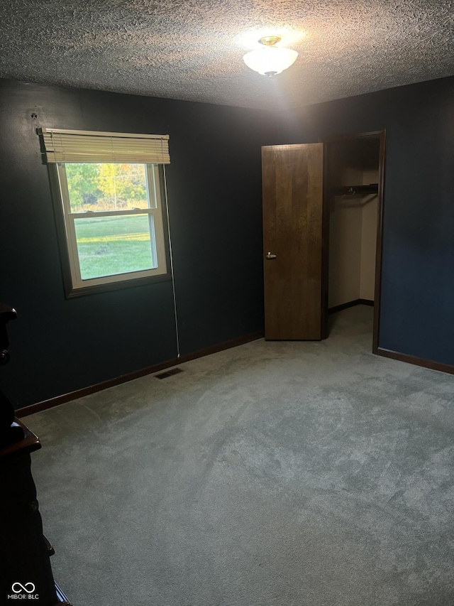 empty room with a textured ceiling and carpet flooring