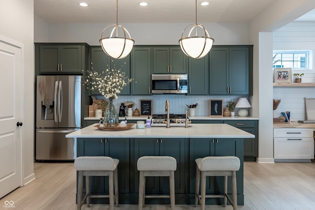 kitchen featuring appliances with stainless steel finishes, a center island with sink, and pendant lighting