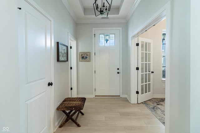 interior space with crown molding, a tray ceiling, light hardwood / wood-style flooring, and an inviting chandelier