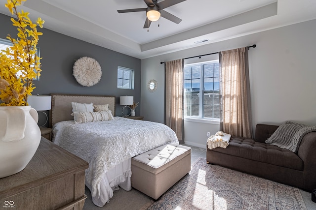 bedroom featuring a raised ceiling and ceiling fan