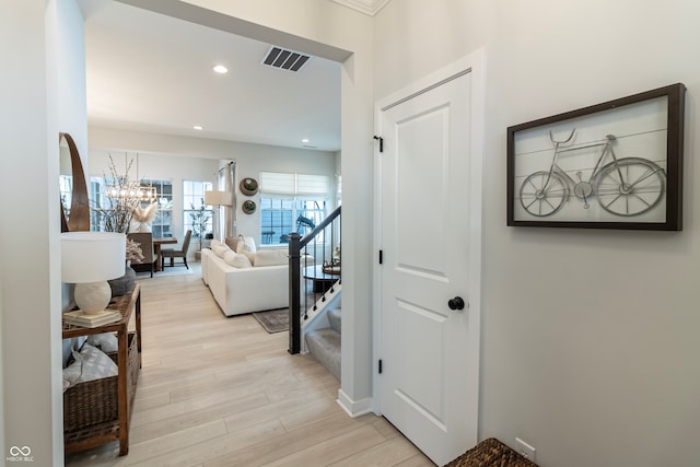 corridor with light hardwood / wood-style floors and an inviting chandelier