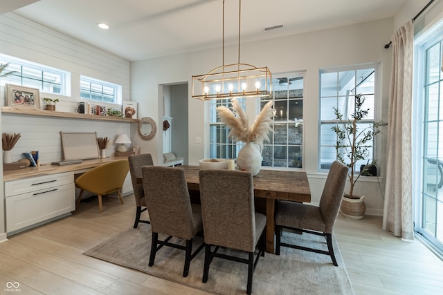 dining room featuring built in desk, light hardwood / wood-style flooring, and an inviting chandelier